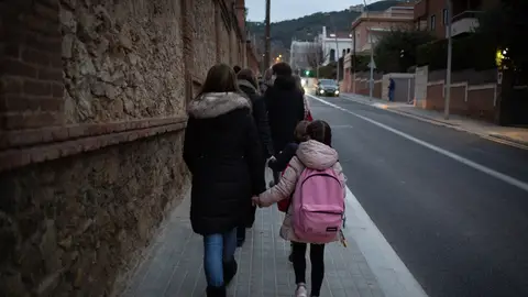 Una mujer lleva de la mano a un niño a su primer día de clase Una mujer lleva de la mano a un niño a su primer día de clase
