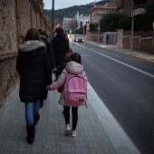 Una mujer lleva de la mano a un niño a su primer día de clase