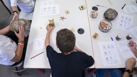 Un ni&ntilde;o en una mesa de un aula con distinto material escolar