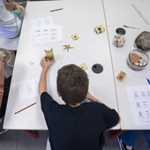 Un niño en una mesa de un aula con distinto material escolar Un niño en una mesa de un aula con distinto material escolar