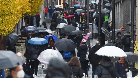 Personas caminan por la calle con paraguas Personas caminan por la calle con paraguas