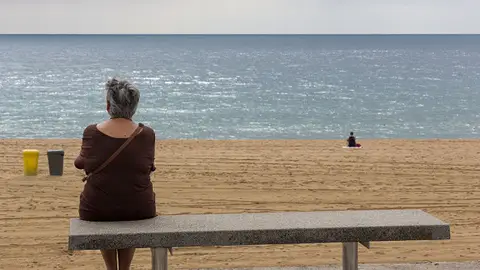 Imagen de archivo. Una mujer sentada en un banco durante un día lluvioso de verano en Barcelona, España. Imagen de archivo. Una mujer sentada en un banco durante un día lluvioso de verano en Barcelona, España.