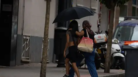 Dos mujeres se protegen de la lluvia con un paraguas. Dos mujeres se protegen de la lluvia con un paraguas.
