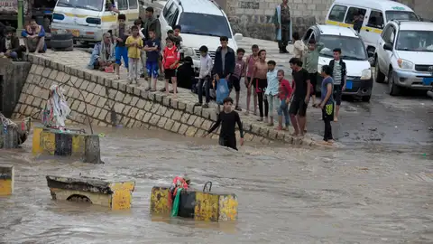 La gente se reúne al lado de una calle inundada tras las fuertes lluvias en Sana'a, Yemen. La gente se reúne al lado de una calle inundada tras las fuertes lluvias en Sana'a, Yemen.