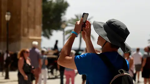 Imagen de archivo. Un joven que lleva un sombrero para protegerse del sol toma una fotografía de la catedral de Palma de Mallorca. Imagen de archivo. Un joven que lleva un sombrero para protegerse del sol toma una fotografía de la catedral de Palma de Mallorca.