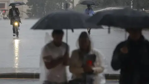 Archivo - Varias personas con paraguas bajo la lluvia - Archivo - Varias personas con paraguas bajo la lluvia -
