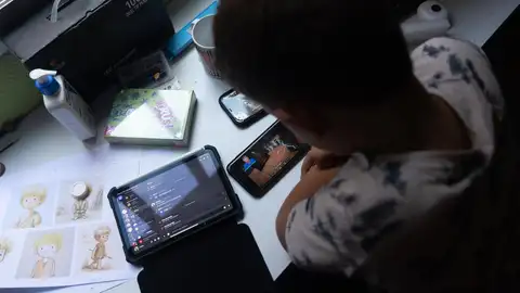 Archivo - Un niño usa el teléfono móvil y una tablet Archivo - Un niño usa el teléfono móvil y una tablet