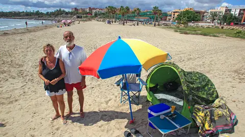 La pareja formada por José Vicente Roca y Charo Ortiz posa junto a hogar en la playa de San Gabriel (Alicante) La pareja que duerme en una playa de Alicante por no poder pagar el alquiler: "Es imposible"