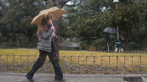 Una mujer pasea bajo la lluvia en Madrid 