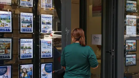 Imagen de archivo de una mujer mirando el escaparate de una inmobiliaria La compraventa de viviendas crece un 19,4% en julio y deja atrás dos meses de caídas