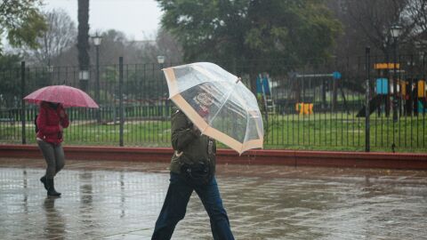 Dos personas se protegen de la lluvia bajo su paraguas.