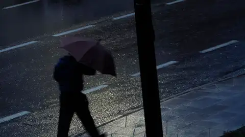 Un hombre se protege del viento y de la lluvia con un paraguas Un hombre se protege del viento y de la lluvia con un paraguas