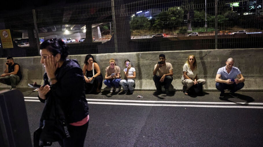 Personas buscan refugio a un lado de una carretera en Tel Aviv tras el sonido de las sirenas/ REUTERS/Tomer Appelbaum 