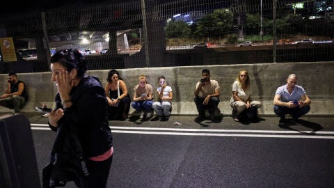 Personas buscan refugio a un lado de una carretera en Tel Aviv tras el sonido de las sirenas/ REUTERS/Tomer Appelbaum 