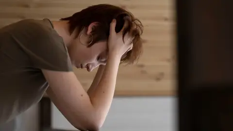 Persona joven cabizbaja apoyando los codos sobre una baranda Persona joven cabizbaja apoyando los codos sobre una baranda