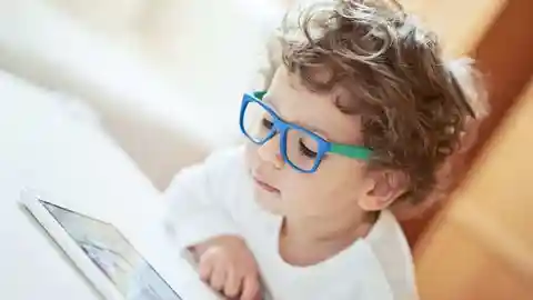 Niño con gafas leyendo en una tablet Niño con gafas leyendo en una tablet