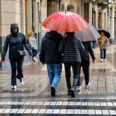 Varias personas se protegen de la lluvia en Logroño.