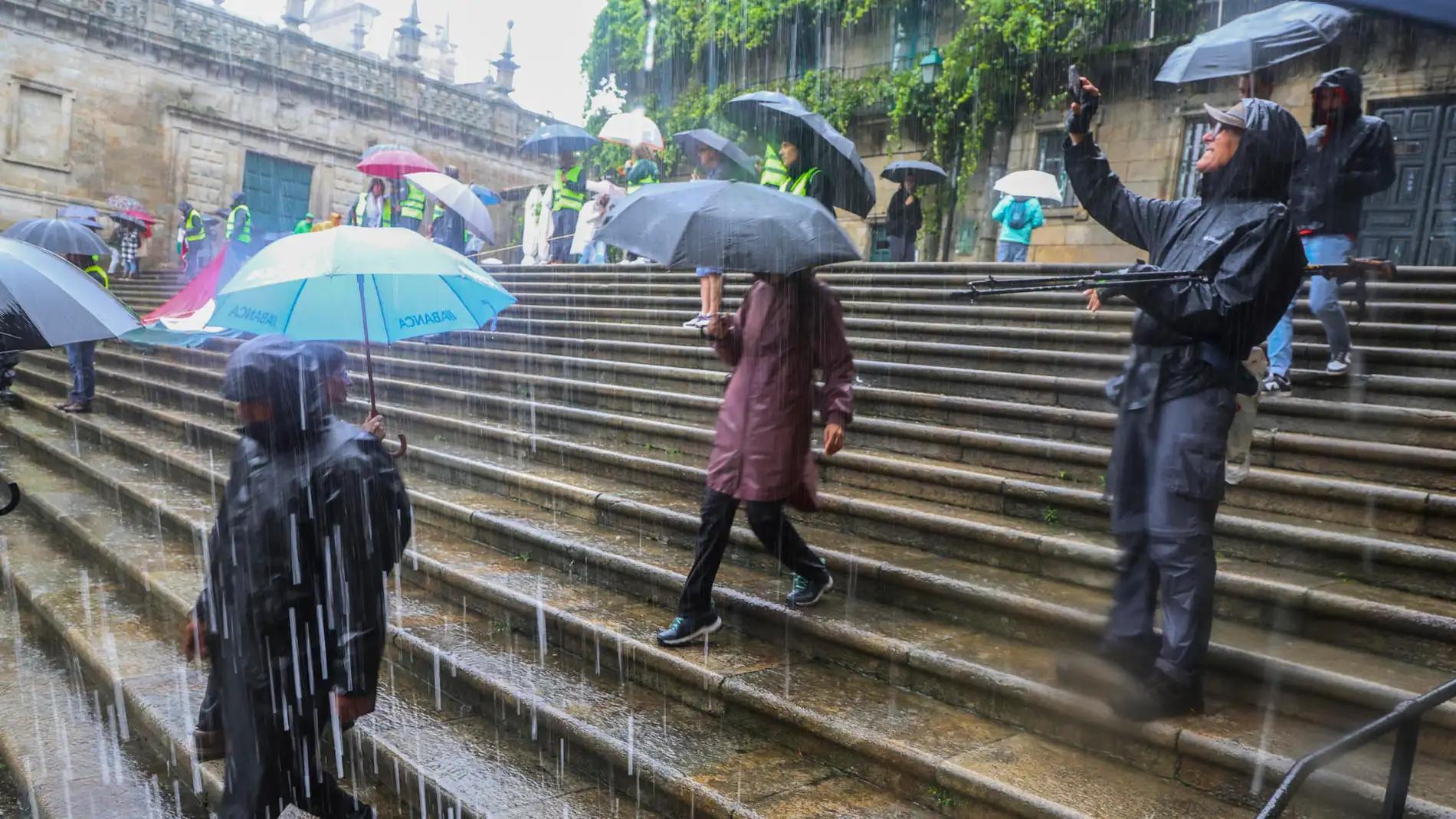 Turistas y peregrinos intentan protegerse de fuertes precipitaciones en la Plaza de la Quintana. Turistas y peregrinos intentan protegerse de fuertes precipitaciones en la Plaza de la Quintana.