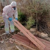 Un operario con protección maneja material de construcción con amianto