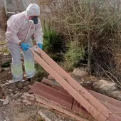 Un operario con protección maneja material de construcción con amianto Un operario con protección maneja material de construcción con amianto