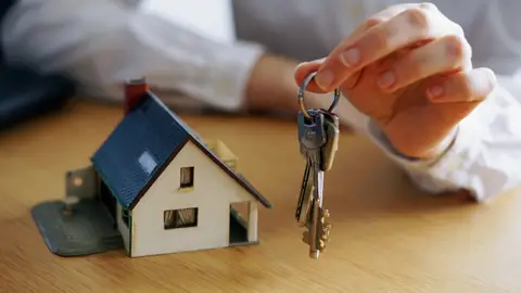 Juego de llaves junto a una casa en miniatura Juego de llaves junto a una casa en miniatura