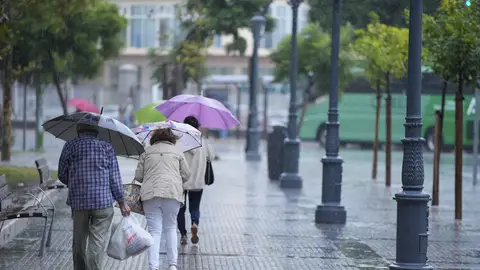 Transeúntes bajo la lluvia con paraguas en Andalucía Transeúntes bajo la lluvia con paraguas en Andalucía