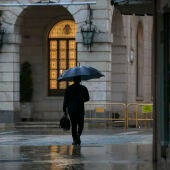 Transeúnte refugiado de la lluvia con paraguas 