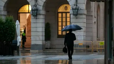 Una persona se protege de la lluvia con un paraguas. Una persona se protege de la lluvia con un paraguas.
