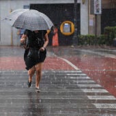 Una mujer camina por un paso de peatones bajo una intensa lluvia en una imagen de archivo. 