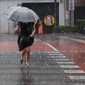 Una mujer camina por un paso de peatones bajo una intensa lluvia en una imagen de archivo. Una mujer camina por un paso de peatones bajo una intensa lluvia en una imagen de archivo.