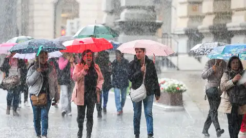 Personas se protegen de la lluvia con paraguas en Bilbao Personas se protegen de la lluvia con paraguas en Bilbao