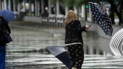 Una mujer se intenta proteger de la fuerte lluvia y el viento con un paraguas, en una imagen de archivo.