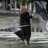 Una mujer se intenta proteger de la fuerte lluvia y el viento con un paraguas, en una imagen de archivo.