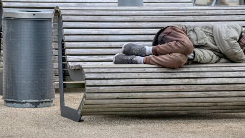 Una persona dormint en un banc, en situaci&oacute; d'excusi&oacute; social i residencial extrema