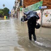 Una persona pasa por una calle que se ha inundado debido a las fuertes lluvias y granizo registrado este miércoles en Málaga.