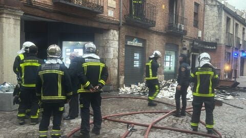 Efectivos de bomberos junto al edificio que ha sufrido un incendio