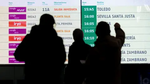 Viajeros contemplando un panel con información de trenes Viajeros contemplando un panel con información de trenes
