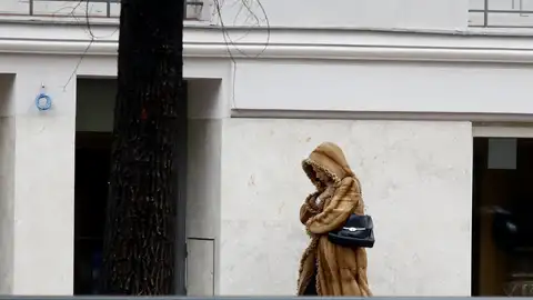 Una mujer se protege del frío con un abrigo Una mujer se protege del frío con un abrigo