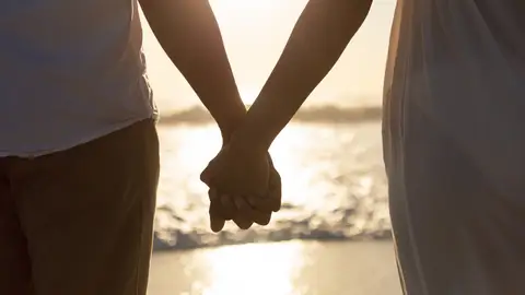 Imagen de una pareja con las manos entrelazadas en la playa Imagen de una pareja con las manos entrelazadas en la playa