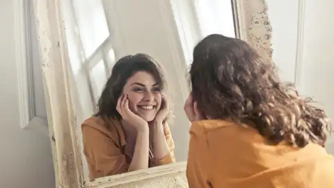 Una mujer feliz mirándose a un espejo Una mujer feliz mirándose a un espejo