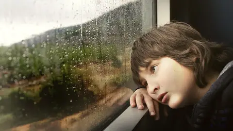 Niño mirando por la ventana Niño mirando por la ventana