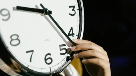 Una persona cambiando la hora de un reloj Una persona cambiando la hora de un reloj