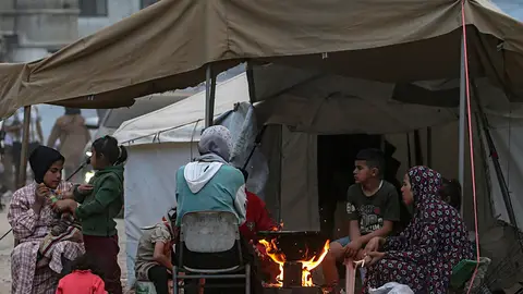 Miembros de una familia palestina desplazada internamente preparan comida sobre un fuego fuera de su tienda después de huir del norte de Gaza Israel anuncia que amplía ofensiva en el sur de Gaza donde "se anexionarán zonas"