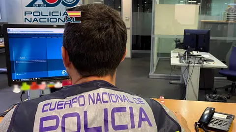 Un agente de policía revisando un ordenador Un agente de policía revisando un ordenador