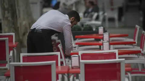 Un camarero limpia las mesas de un bar en Sevilla Un camarero limpia las mesas de un bar en Sevilla