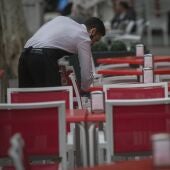 Un camarero limpia las mesas de un bar en Sevilla