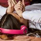 Una adolescente llora tumbada en su cama 