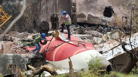 Trabajadores indios que retiran los restos del avión de Air India con una grúa del lugar del accidente Trabajadores indios que retiran los restos del avión de Air India con una grúa del lugar del accidente