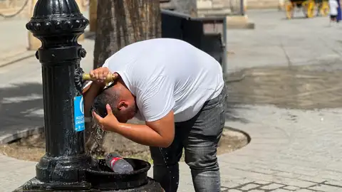 Un hombre refrescándose en una fuente en Sevilla Un hombre refrescándose en una fuente en Sevilla