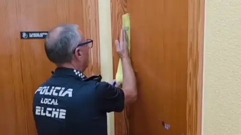 Un agente de la Policía Local de Elche precintando la casa en la que los detenidos tenían la actividad irregular de cuidado de personas dependientes. Un agente de la Policía Local de Elche precintando la casa en la que los detenidos tenían la actividad irregular de cuidado de personas dependientes.